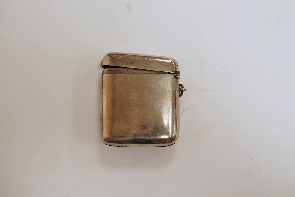 A George V silver mounted rectangular cigarette box, with later engraved inscription, Birmingham, 1932, 13.7cm, together with a similar silver vesta case and two modern silver wine labels. Condition - poor to fair